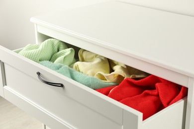 Photo of Cluttered chest of drawers indoors, closeup. Clothes in mess