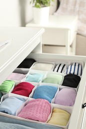 Photo of Chest of drawers with different folded clothes indoors, closeup