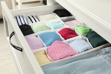 Chest of drawers with different folded clothes, closeup