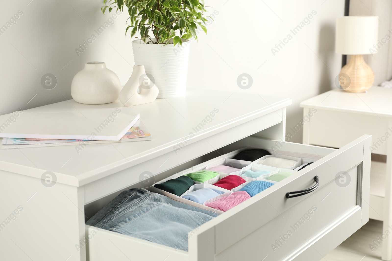 Photo of Chest of drawers with different folded clothes indoors