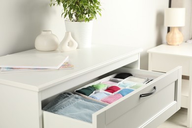 Photo of Chest of drawers with different folded clothes indoors