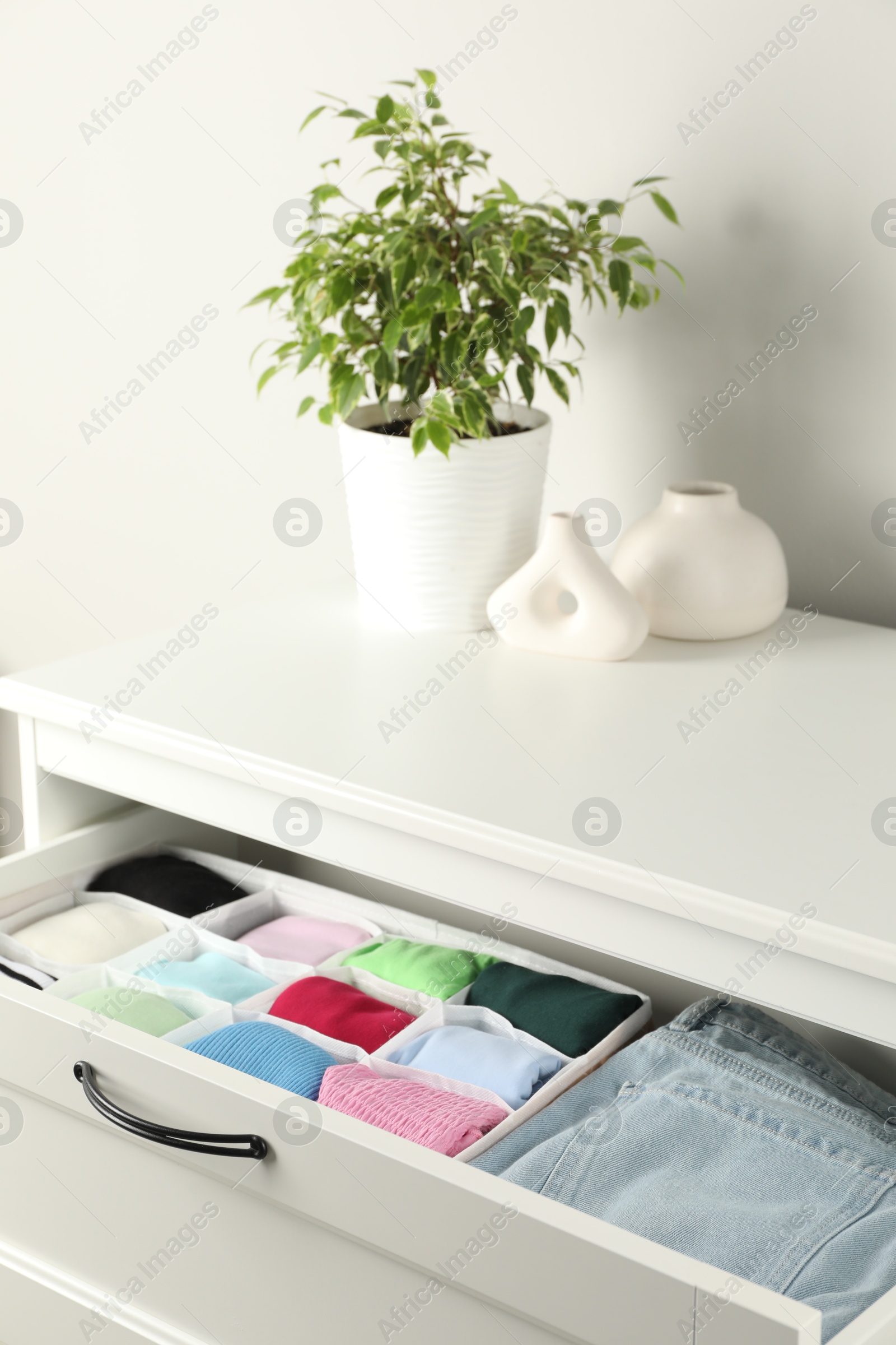 Photo of Chest of drawers with different folded clothes indoors