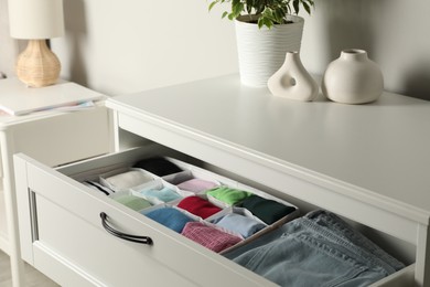 Chest of drawers with different folded clothes indoors