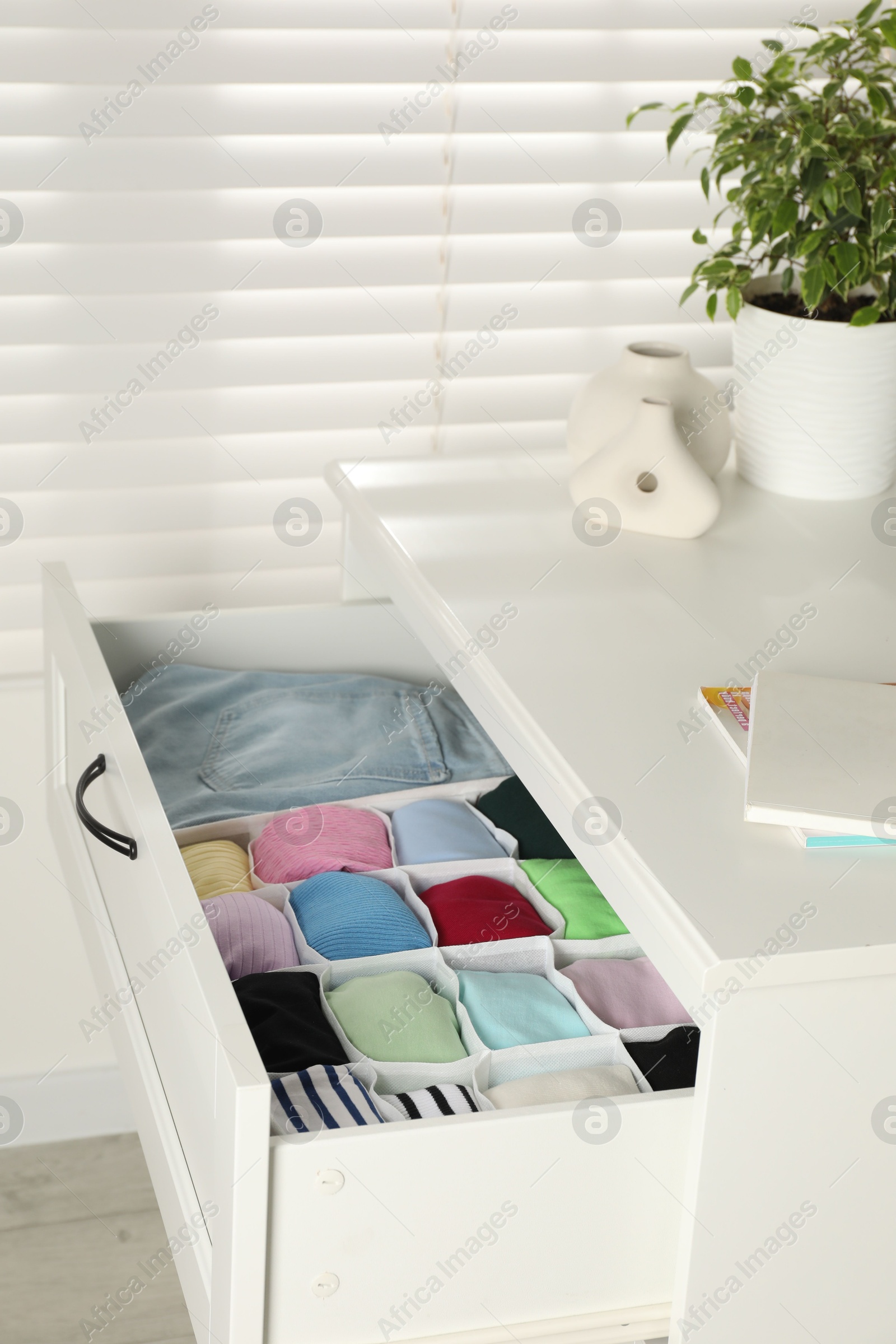 Photo of Chest of drawers with different folded clothes indoors