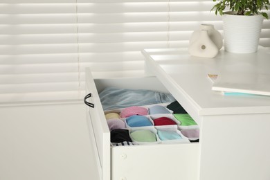 Chest of drawers with different folded clothes indoors