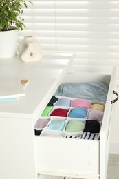 Chest of drawers with different folded clothes indoors