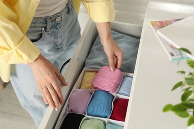 Woman organizing clothes in chest of drawers indoors, closeup