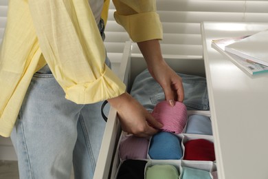 Photo of Woman organizing clothes in chest of drawers indoors, closeup