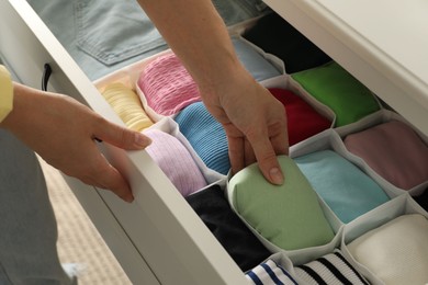 Woman organizing clothes in chest of drawers indoors, closeup