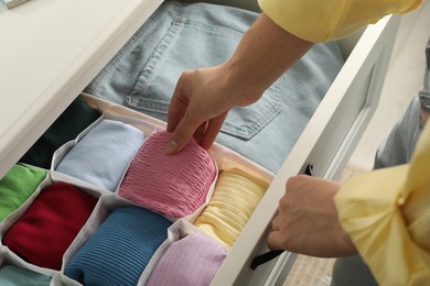 Photo of Woman organizing clothes in chest of drawers indoors, closeup