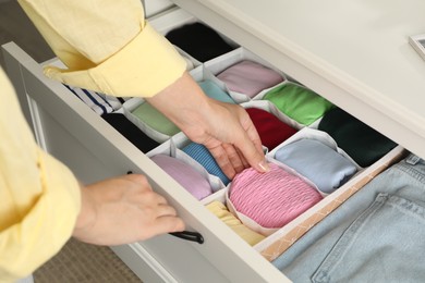 Photo of Woman organizing clothes in chest of drawers indoors, closeup