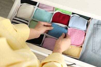 Photo of Woman organizing clothes in chest of drawers indoors, above view