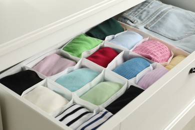 Photo of Chest of drawers with different folded clothes, closeup