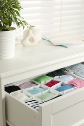 Photo of Chest of drawers with different folded clothes indoors, closeup