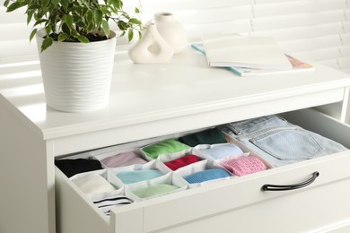 Chest of drawers with different folded clothes indoors, closeup