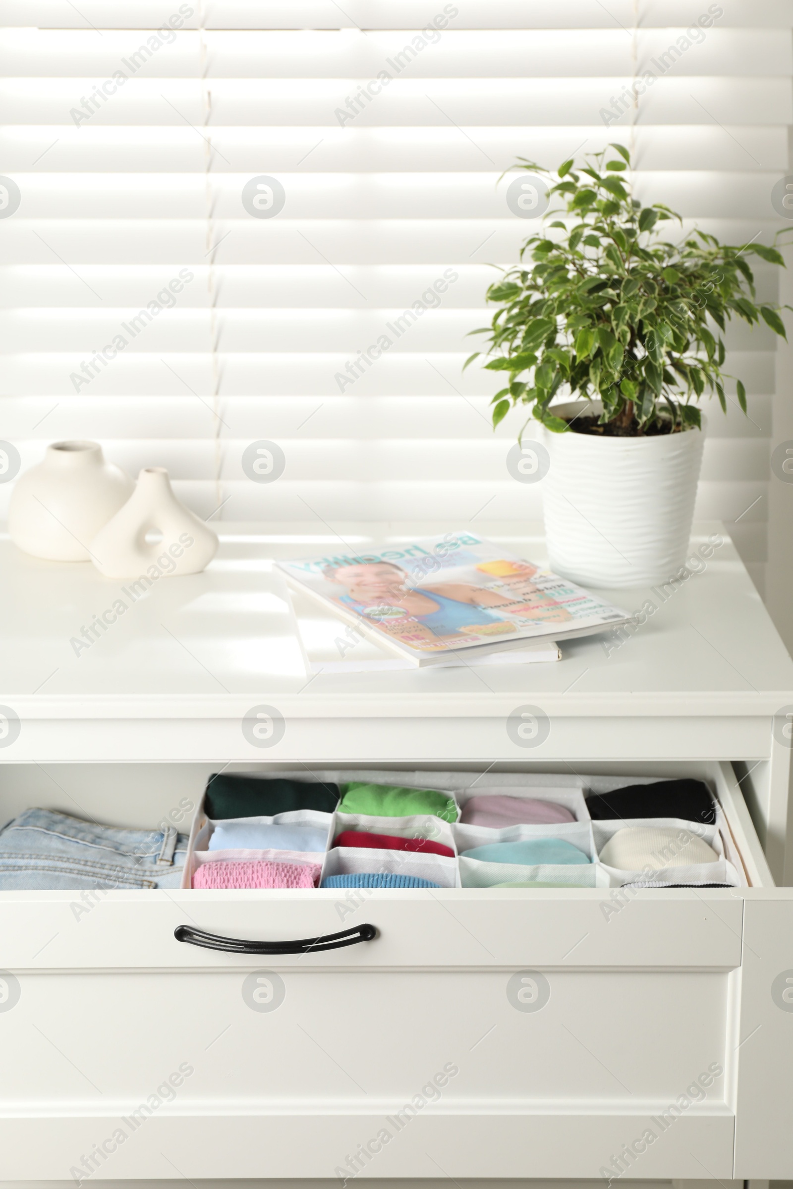 Photo of Chest of drawers with different folded clothes indoors