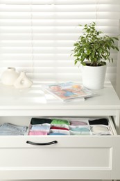 Photo of Chest of drawers with different folded clothes indoors