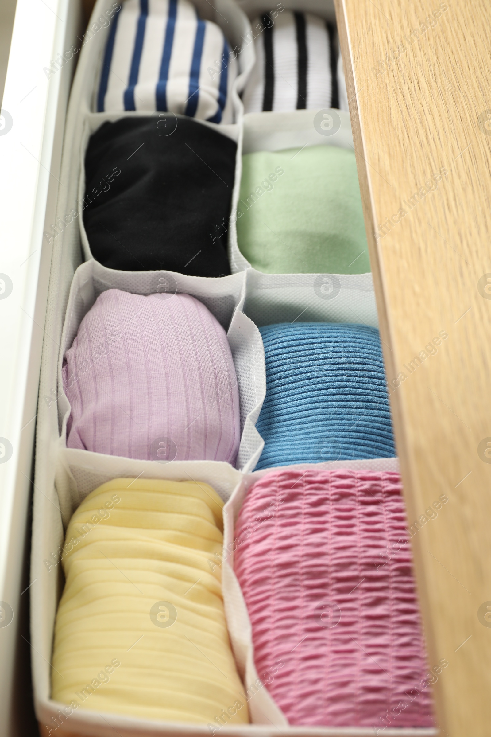 Photo of Chest of drawers with different folded clothes, closeup