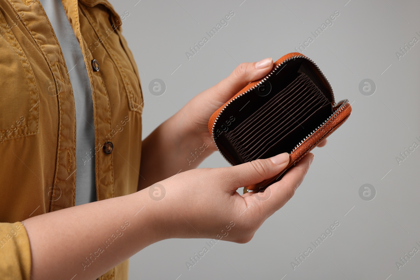 Photo of Woman with empty wallet on grey background, closeup