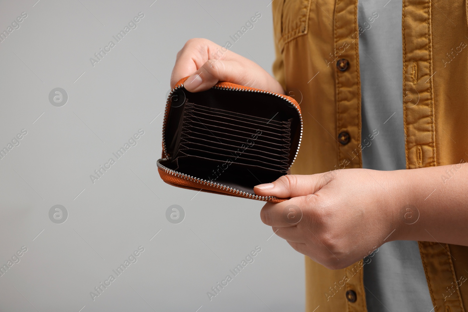 Photo of Woman with empty wallet on grey background, closeup