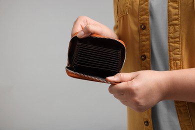 Photo of Woman with empty wallet on grey background, closeup