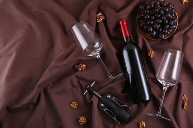 Photo of Flat lay composition with wing corkscrew and wine on brown fabric, space for text