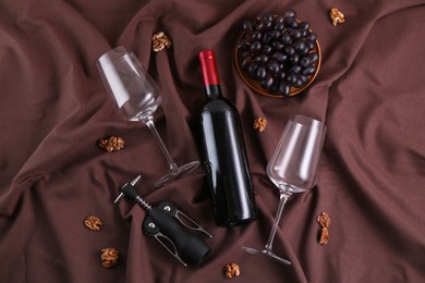 Photo of Flat lay composition with wing corkscrew and wine on brown fabric