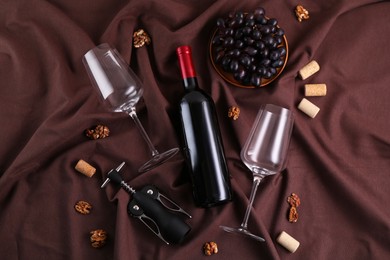 Photo of Flat lay composition with wing corkscrew and wine on brown fabric