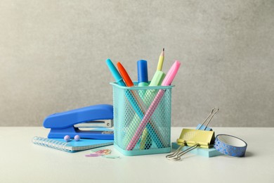 Stapler, holder and other different stationery on white table