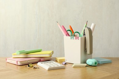 Photo of Stapler, holder and other different stationery on wooden table