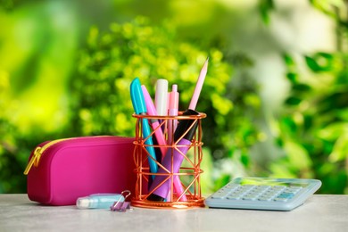 Holder, pencil case, calculator and other different stationery on white table