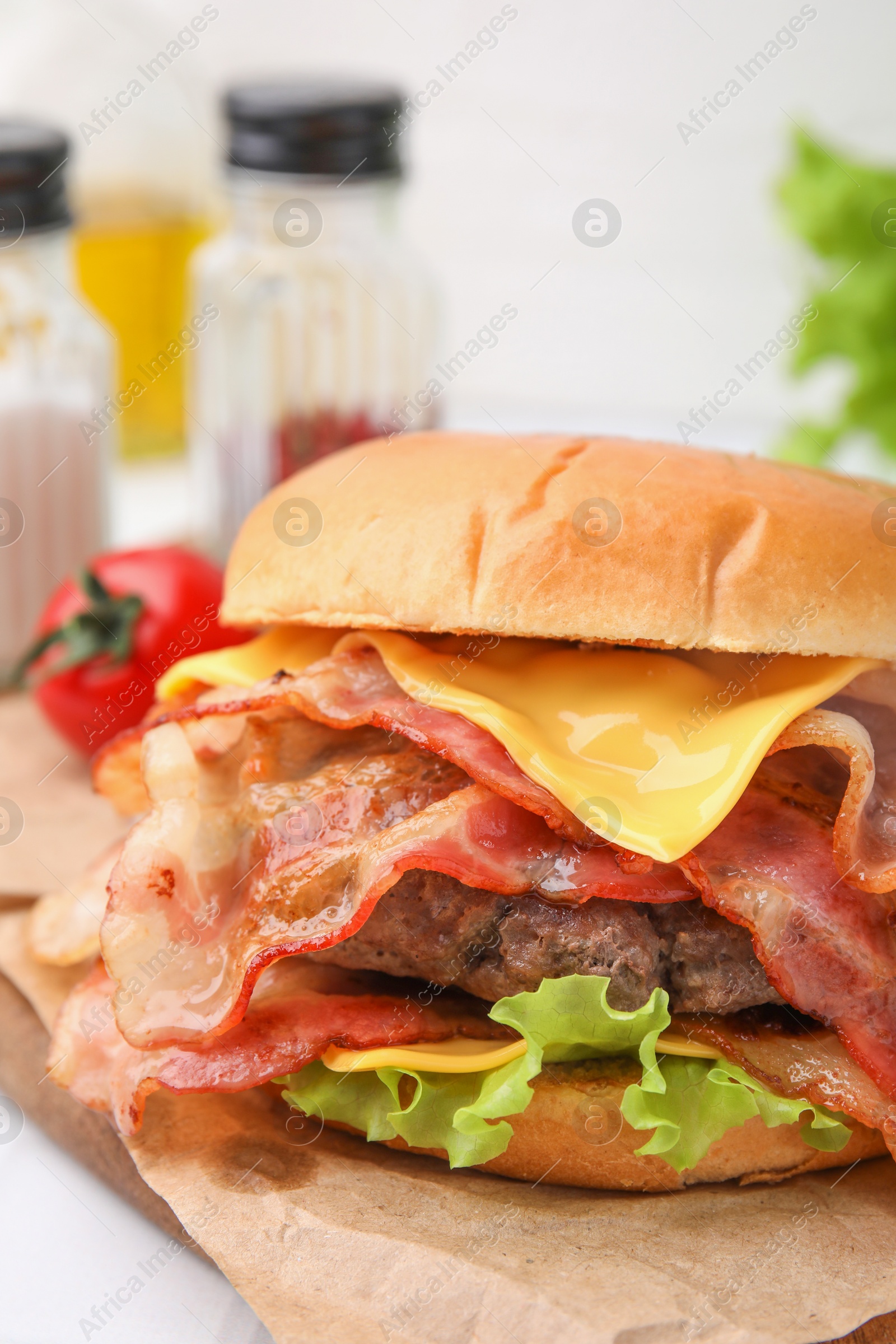 Photo of Delicious burger with bacon, patty and cheese on table, closeup