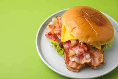 Photo of Delicious burger with bacon, patty and cheese on green background, space for text