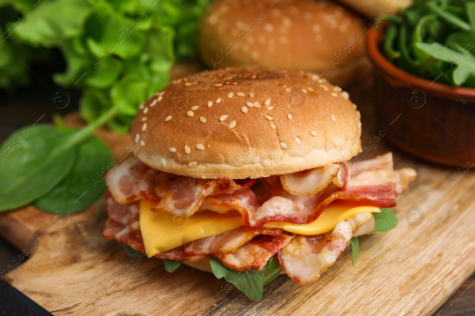 Photo of Delicious burger with bacon and cheese on table