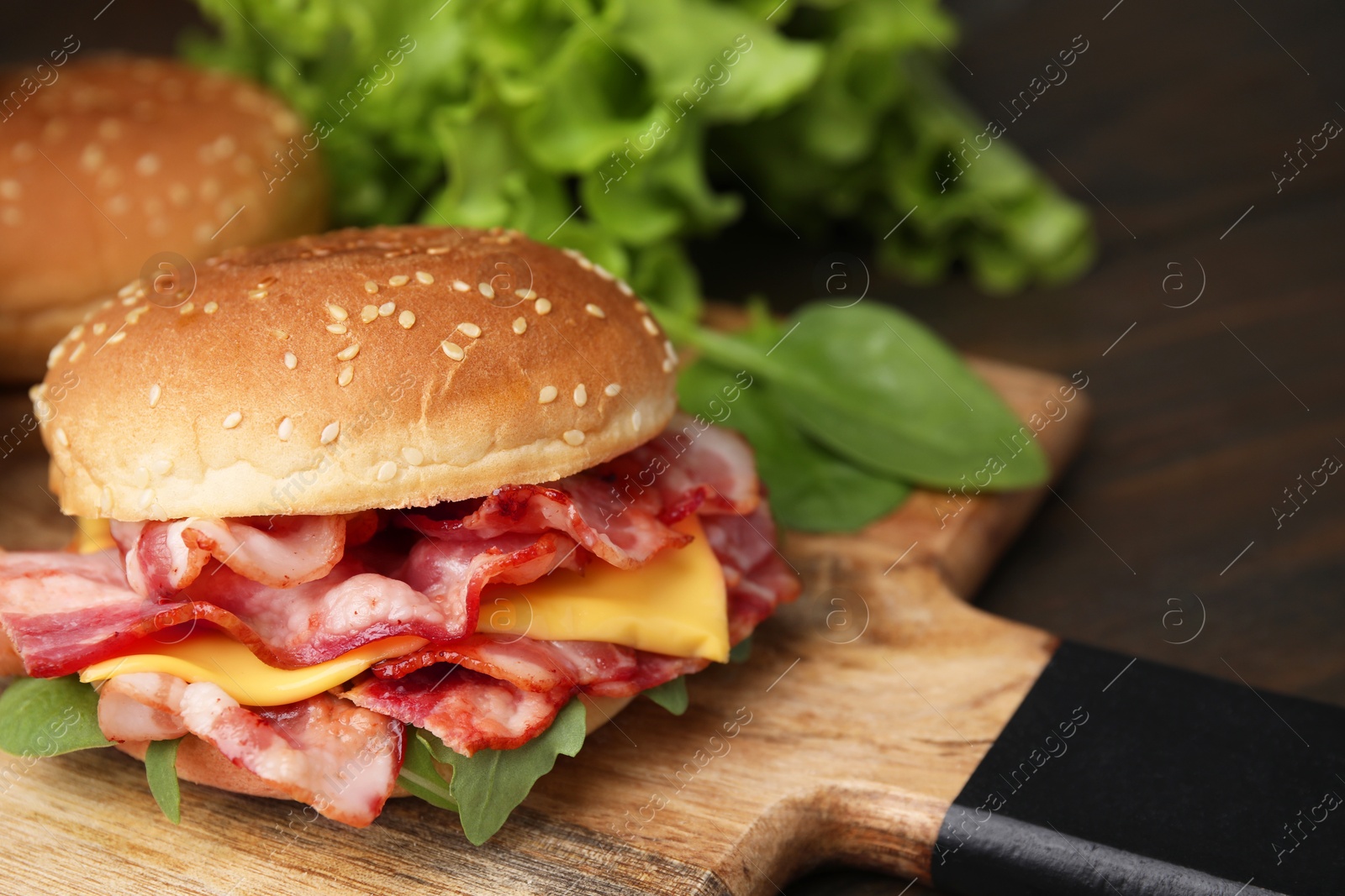 Photo of Delicious burger with bacon and cheese on table