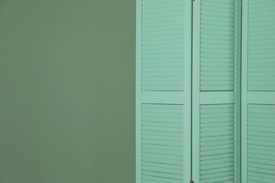 Photo of One folding screen near green wall indoors, space for text