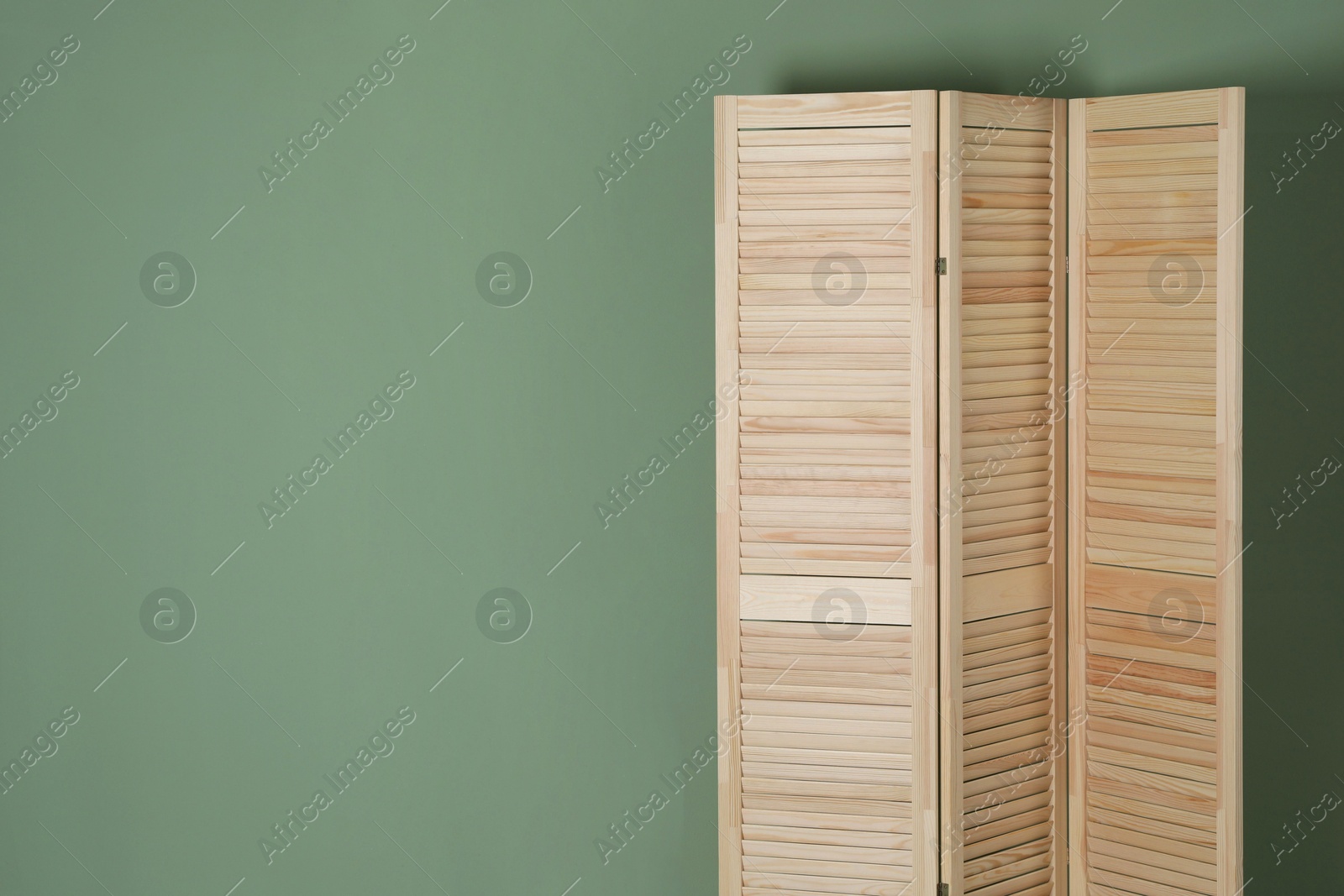 Photo of Wooden folding screen near green wall indoors, space for text