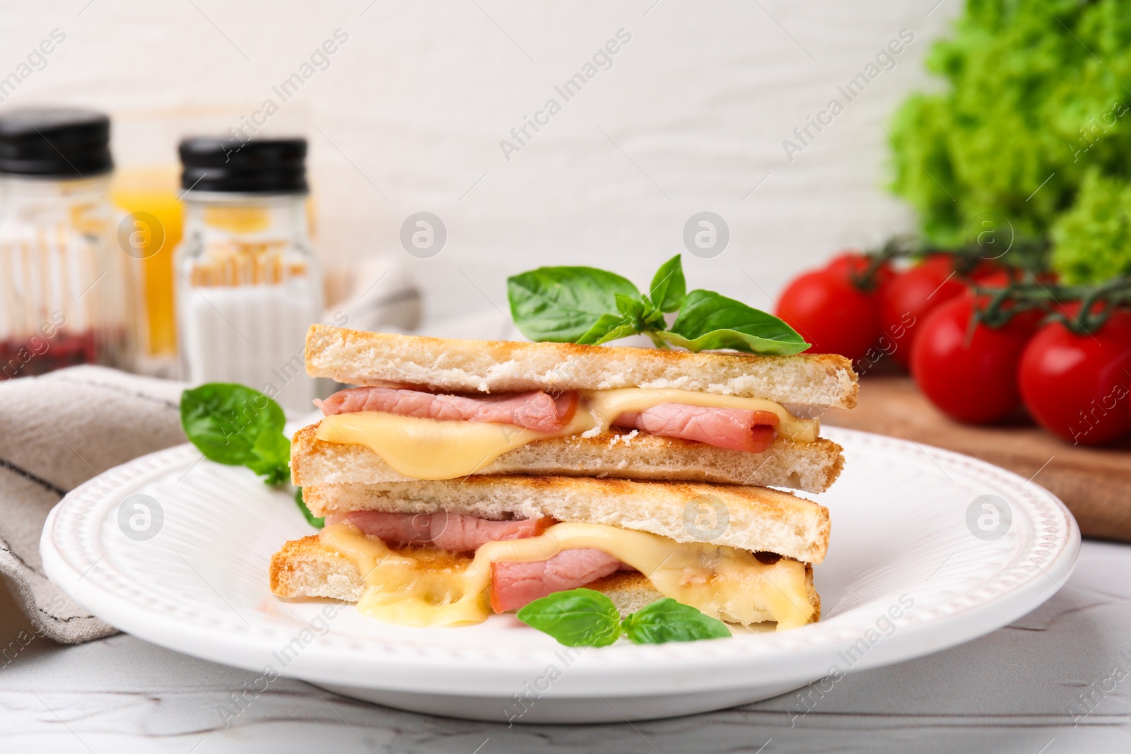 Photo of Pieces of toasted bread with melted cheese, ham and basil on white table