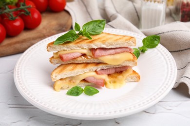 Photo of Pieces of toasted bread with melted cheese, ham and basil on white table