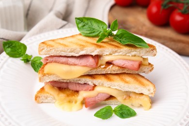 Pieces of toasted bread with melted cheese, ham and basil on table