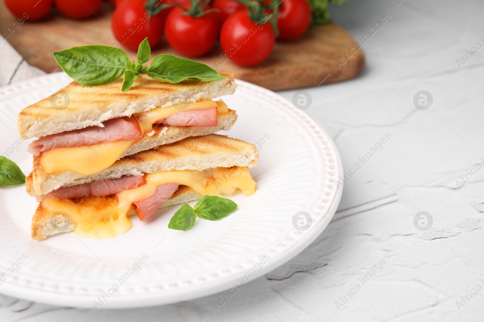 Photo of Pieces of toasted bread with melted cheese, ham, basil and tomatoes on white table. Space for text