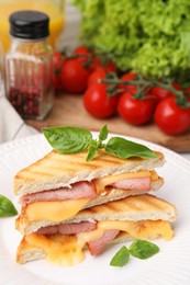 Photo of Pieces of toasted bread with melted cheese, ham and basil on table