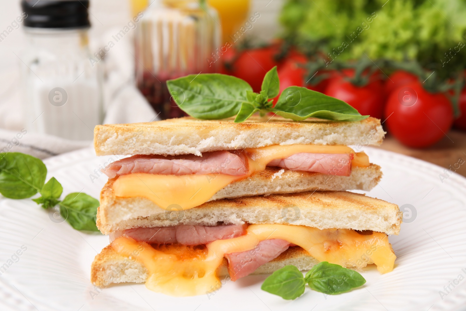 Photo of Pieces of toasted bread with melted cheese, ham and basil on plate, closeup