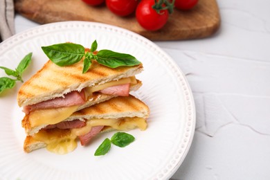 Photo of Pieces of toasted bread with melted cheese, ham and basil on white table