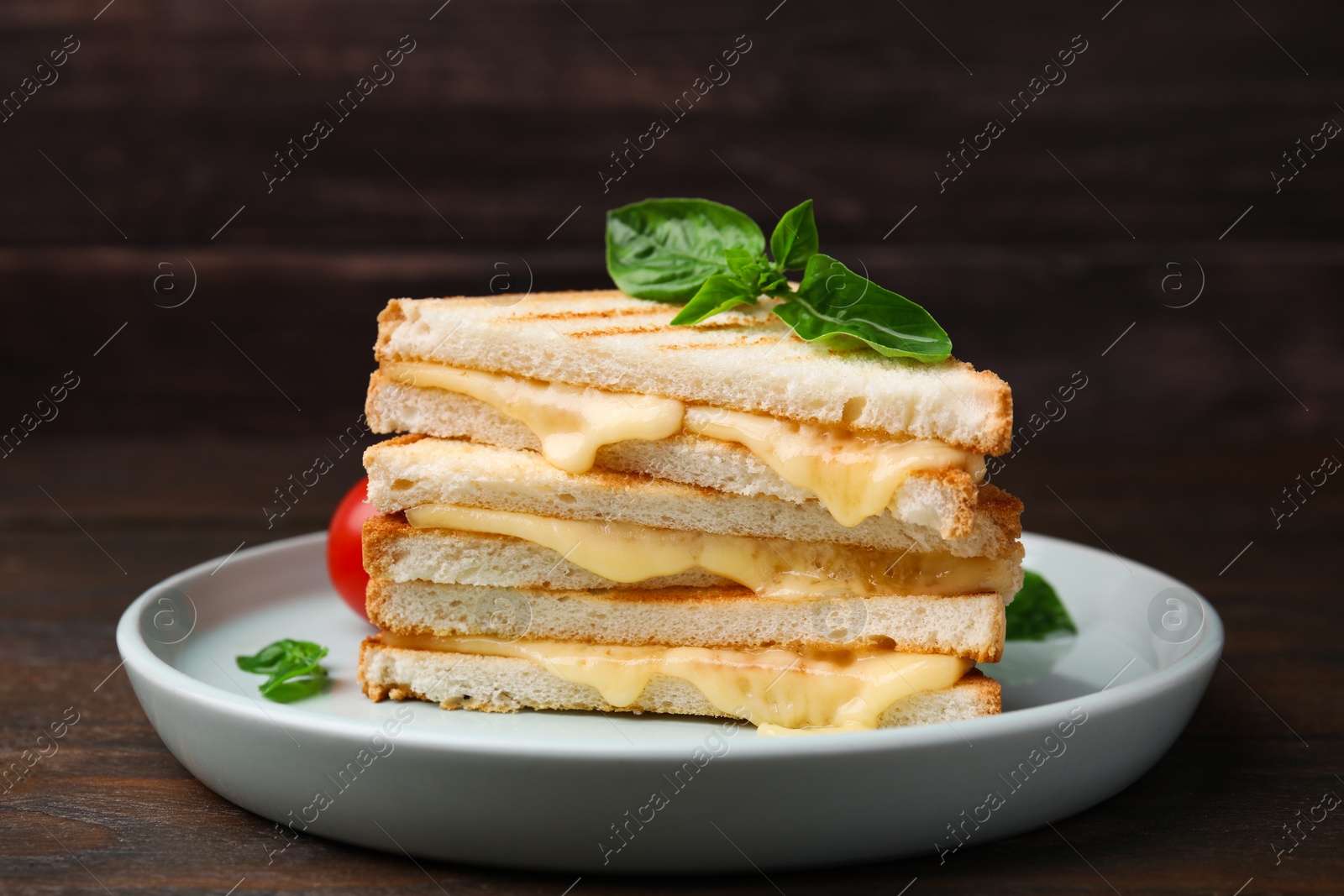 Photo of Pieces of toasted bread with melted cheese and basil on wooden table