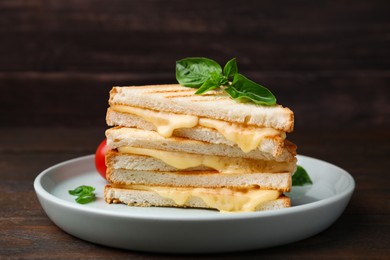 Photo of Pieces of toasted bread with melted cheese and basil on wooden table