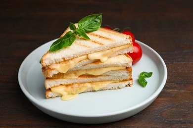 Photo of Pieces of toasted bread with melted cheese, tomato and basil on wooden table