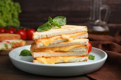 Photo of Pieces of toasted bread with melted cheese and basil on wooden table