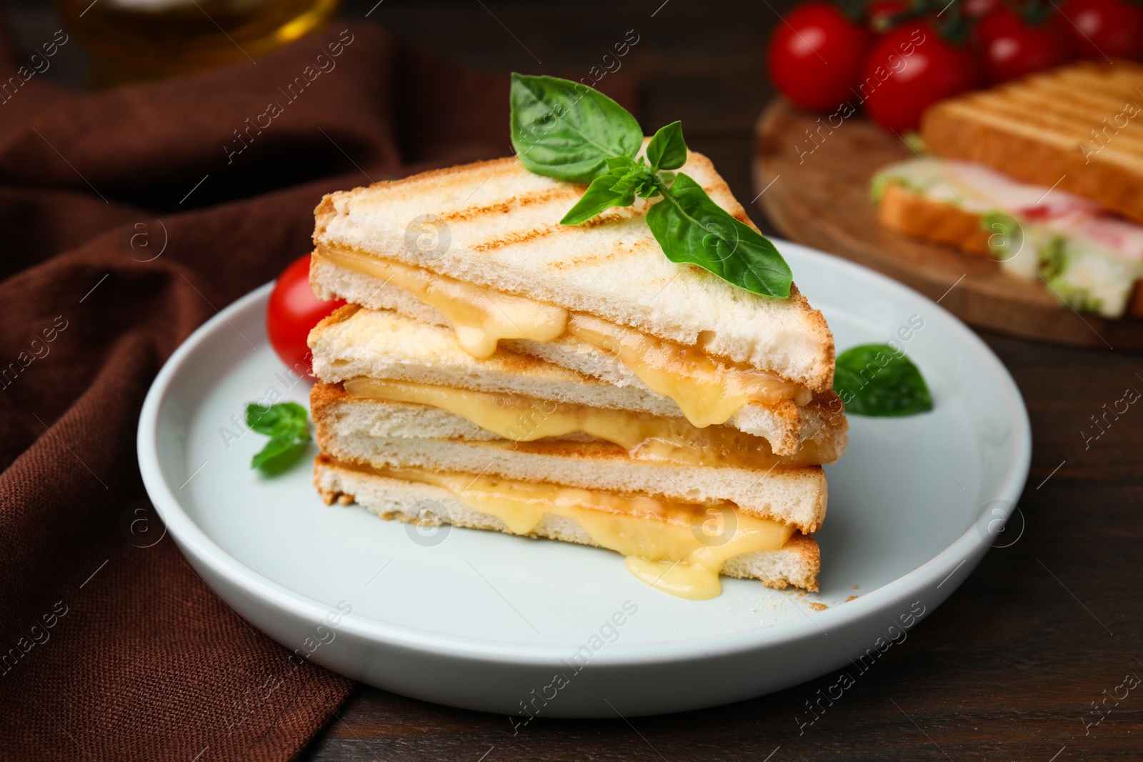 Photo of Pieces of toasted bread with melted cheese and basil on wooden table