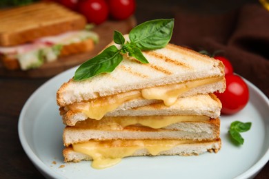 Photo of Pieces of toasted bread with melted cheese and basil on table